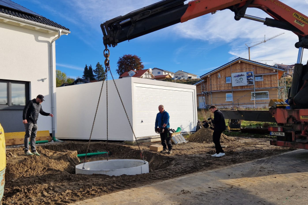 Zisterne bei beim einsetzen in den Baugrube mit dem LKW Kran