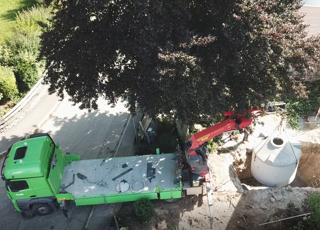 LKW hebt Betonzisterne in das vorbereitete Loch